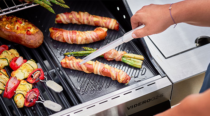 Spargel mit Speck ummantelt wird auf der Grillplatte zubereitet