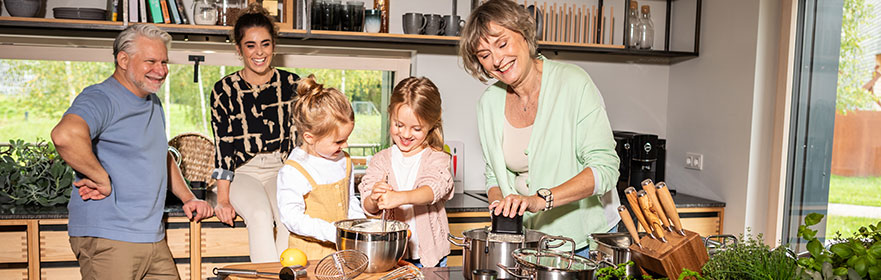 Familie Familie zusammen in der Küche, während Kinder mit Oma Spätzle kochen.