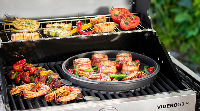 Vario Grillrostsystem Deckel des Dutch Oven mit Fleisch im Vario Grillrostsystem
