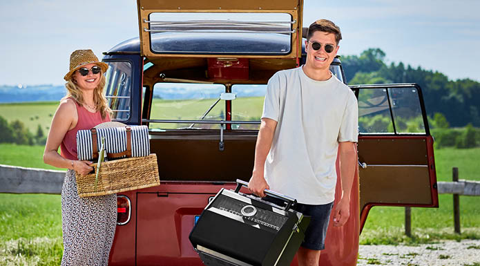 Gasgrill BBQ-Portable Videro G2-P Mann trägt portablen Gasgrill und Frau Picknick-Korb