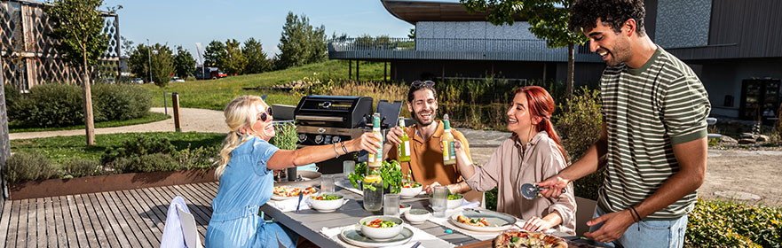 Pizza Vier Freunde sitzen zusammen am Terrassentisch und stoßen mit einer Flasche an